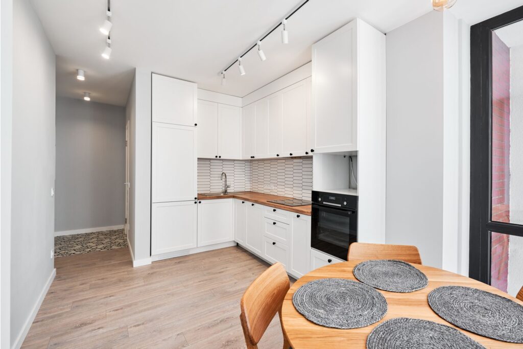Kitchen with white units, a wooden worktop and a round dining table