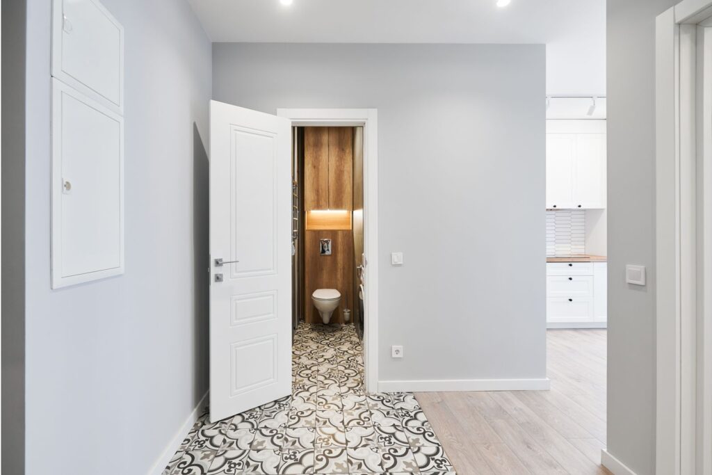 Hallway with a white panelled door and patterned floor tiles