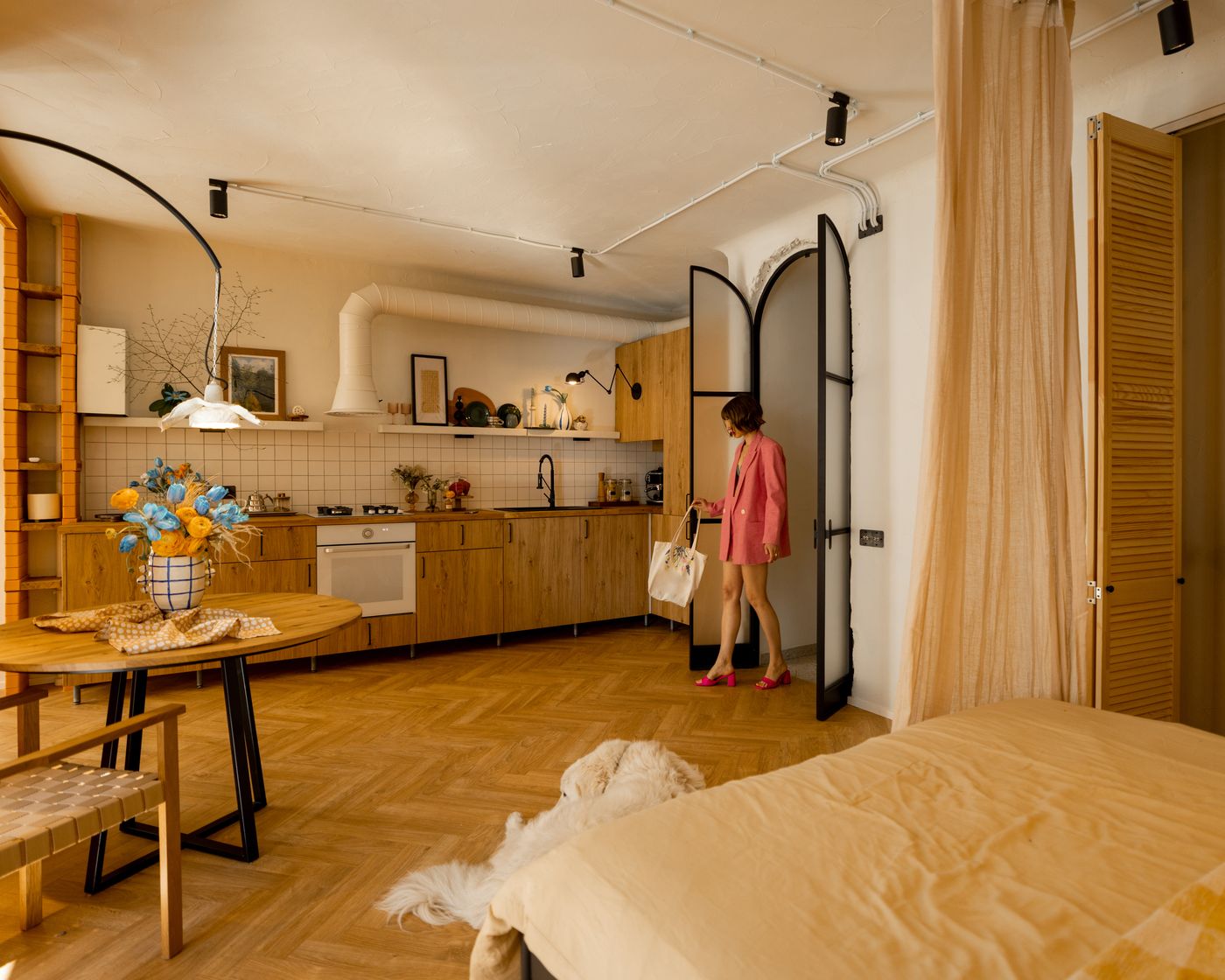 A woman arriving at a bright open-plan flat with a wooden kitchen